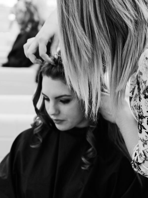 Stellenanzeige Friseur Eine junge Friseurin macht Haar-Styling einer jungen Frau